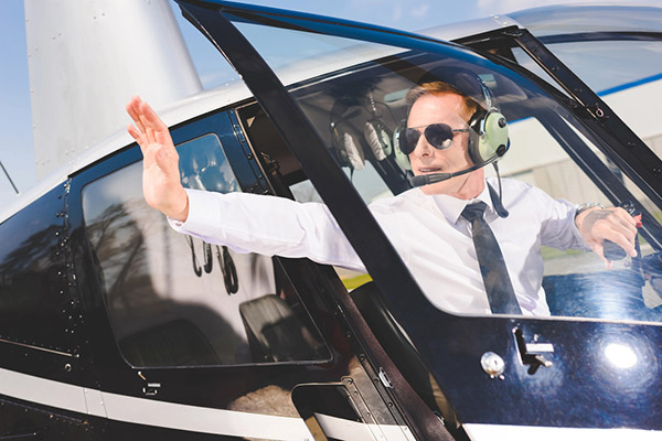 Pilot in sunglasses and headset sitting in helicopter cabin