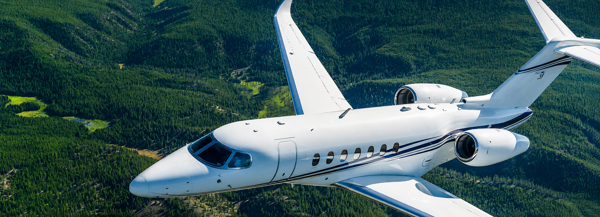 Cessna Citation Longitude in flight over a forest