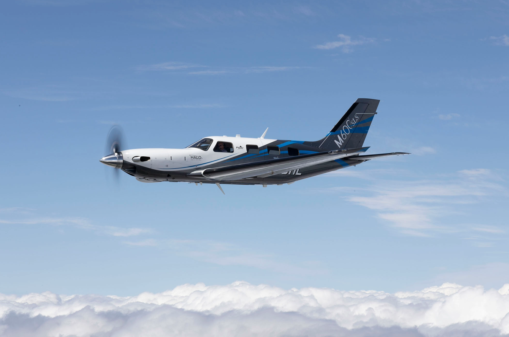 Piper M600 over clouds with blue skies side view
