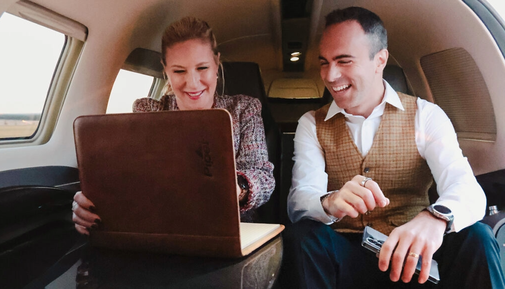 Passengers in cabin looking at computer and smiling