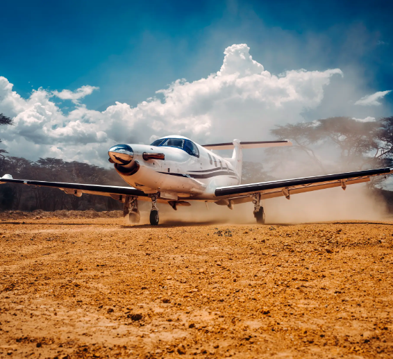 Pilatus PC12 on dusty ground with white clouds and blue sky behind
