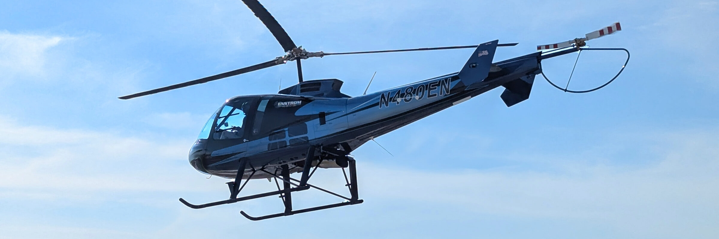 Enstrom 480B Elite helicopter in flight against a blue sky