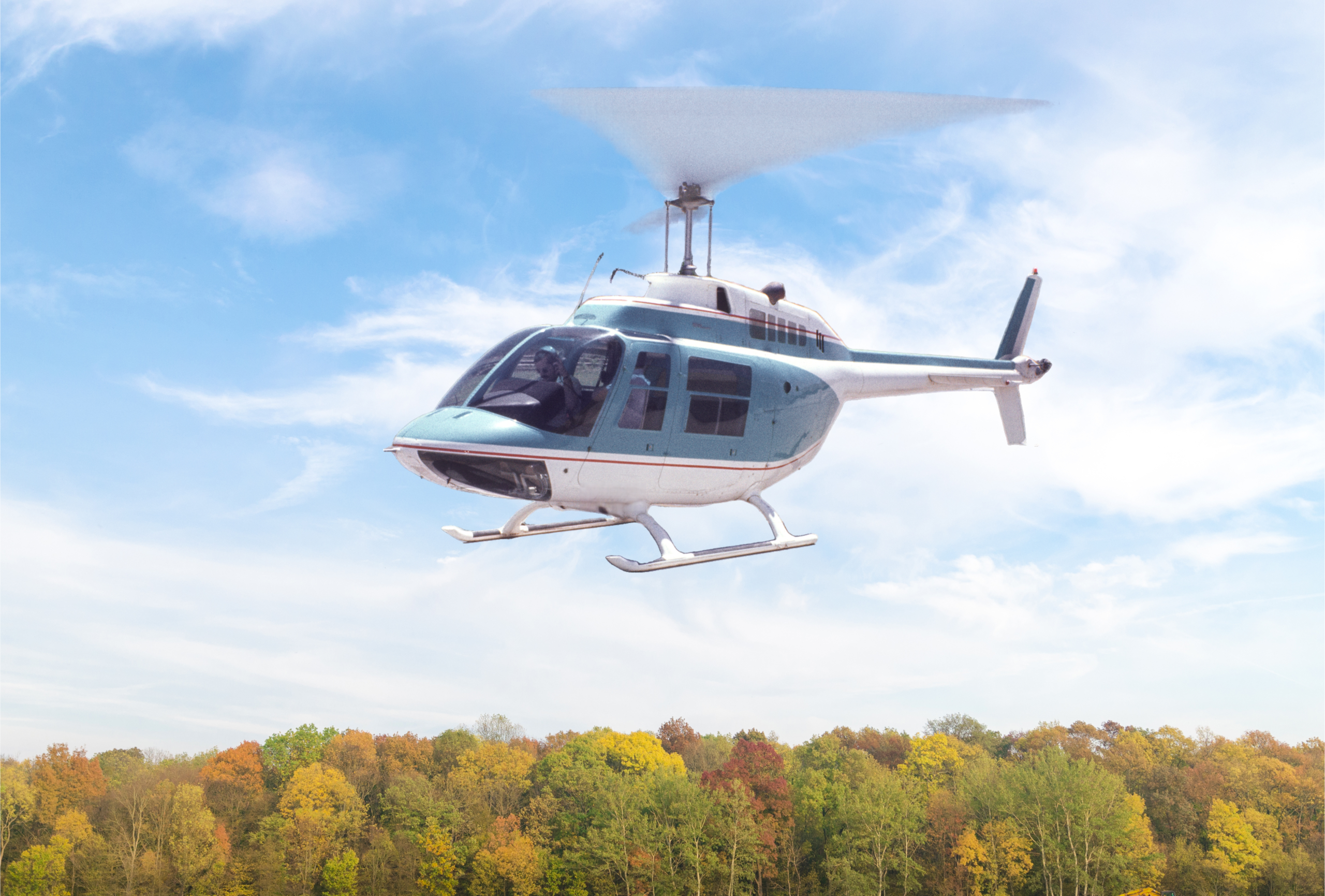 Bell 206B-3 JetRanger helicopter flying over trees