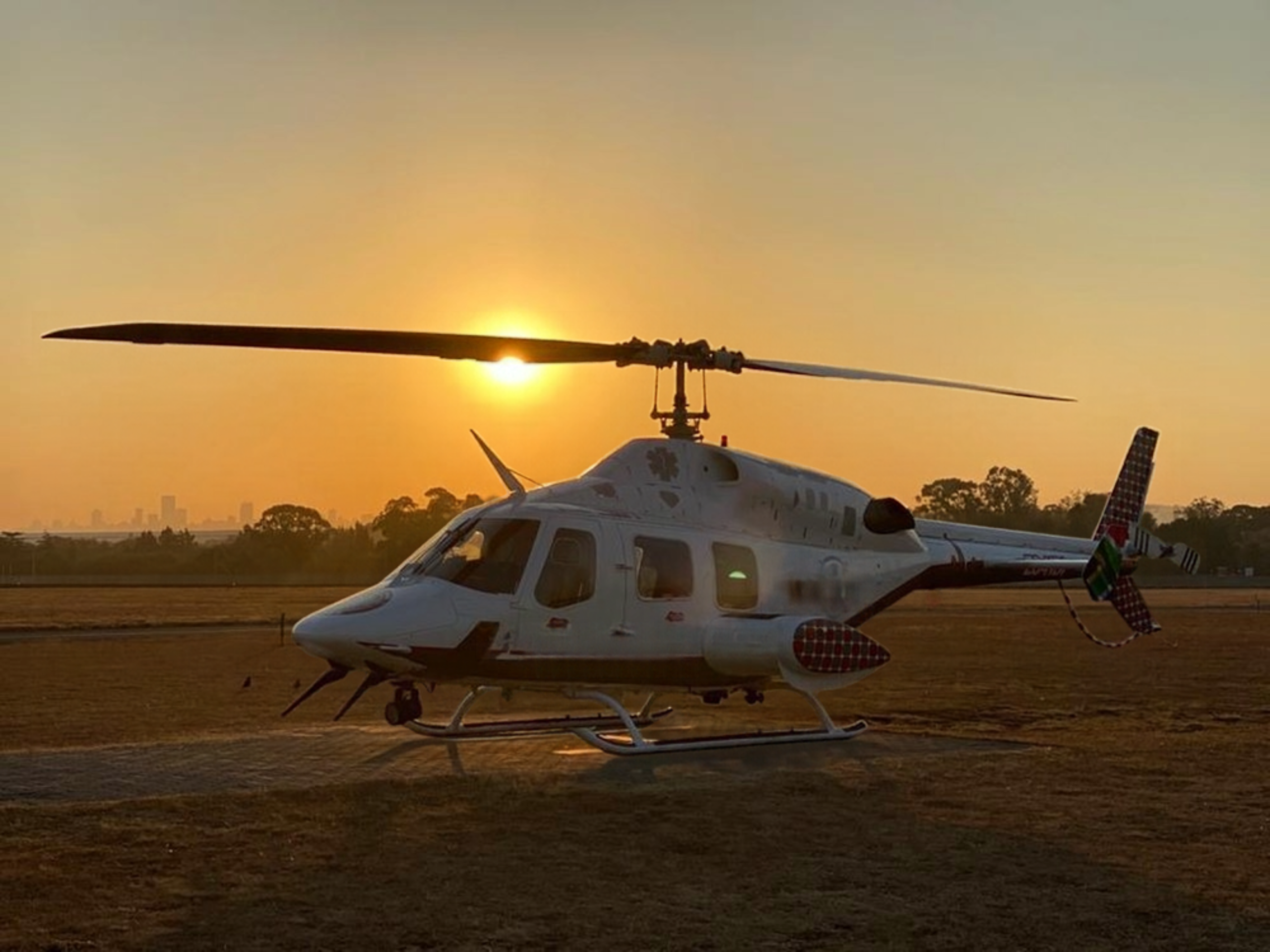 Bell 222 helicopter parked on the ground at sunset